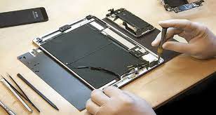 iPad repair in progress: Technician disassembling a tablet with tools on a workbench. ER4Gadgets